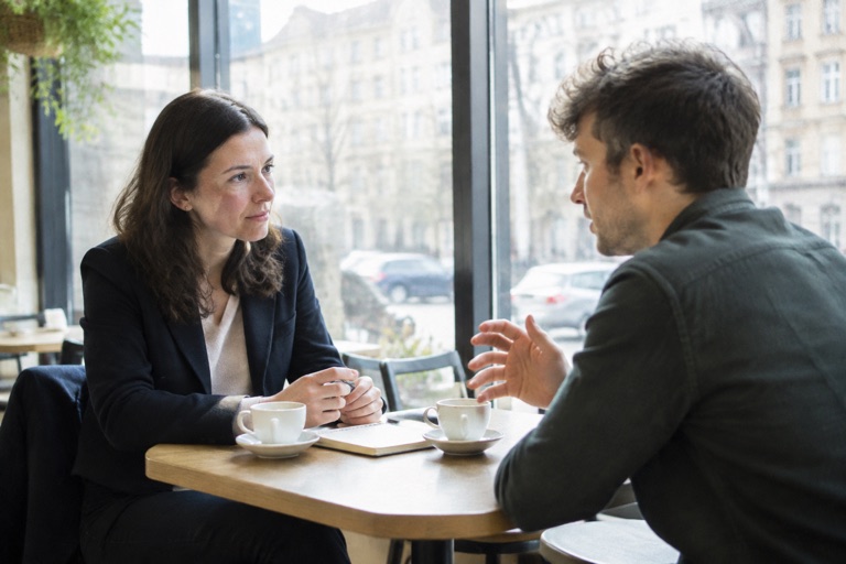 Personalberaterin im Gespräch mit einem Kandidaten an einem Tisch in einem hellen Café