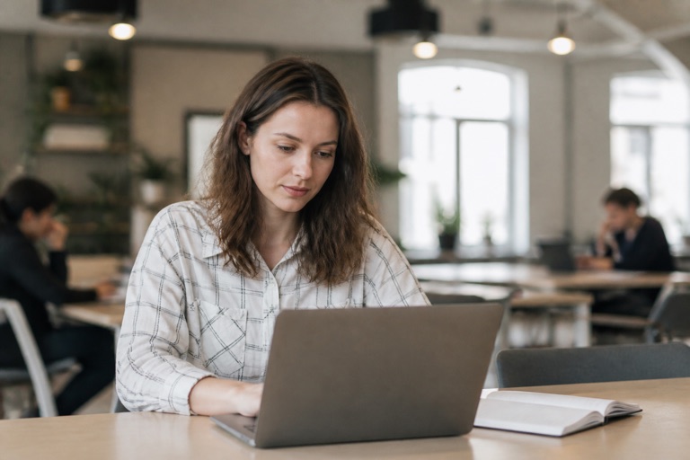 Person sucht am Laptop in einem Coworking-Space nach passenden Stellen