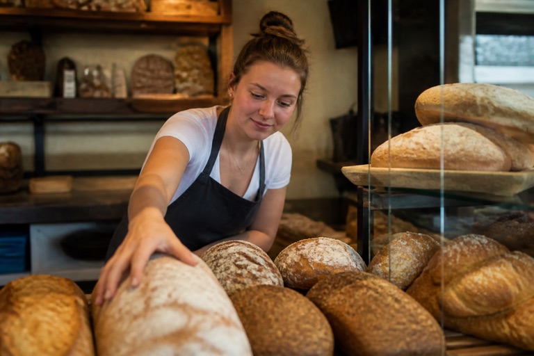 Junge Person arbeitet im Minijob hinter der Theke einer Bäckerei