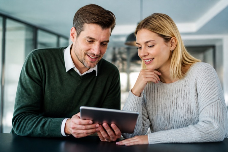 Zwei Kollegen sehen sich gemeinsam Stellenangebote auf einem Tablet an