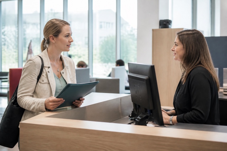 Frau spricht mit einer Beraterin am Servicetresen der Arbeitsagentur