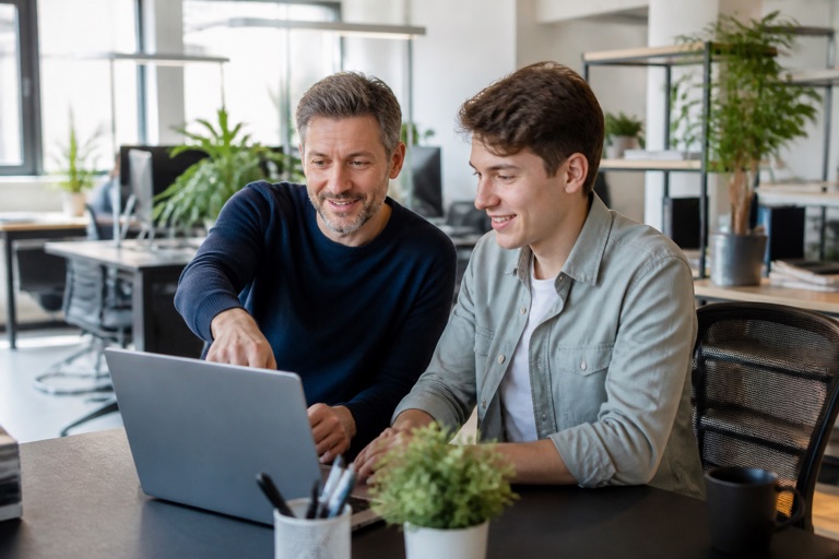 Kollegin arbeitet einen neuen Mitarbeiter in der Probezeit am Laptop ein